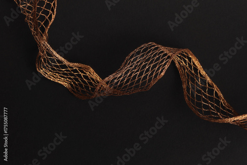 Gold, bronze metallic copper braided wave wire on black. Abstract light, shadow texture background.