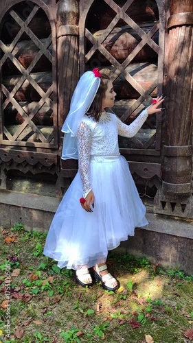A girl in a white dress and a veil, the image of a scary bride, moves like a zombie on the street, in the park on Halloween