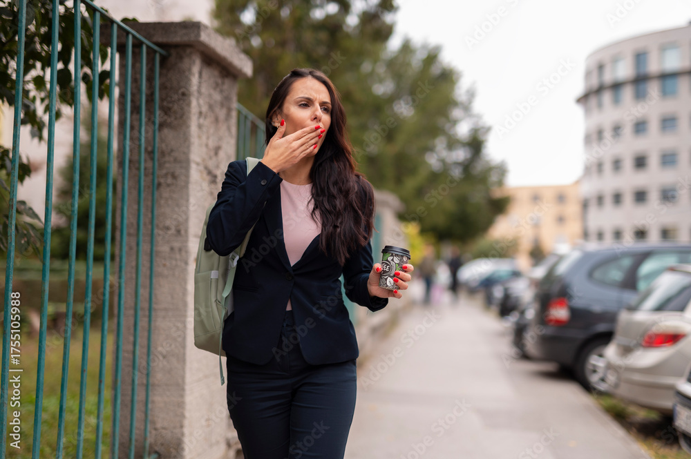 Fototapeta premium Businesswoman yawning while commuting with coffee cup