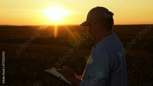 Farmer men works in field with computer tablet. Agronomist works in field. Businessman with tablet computer in hands works in wheat field, checking harvest. Modern concept of agricultural business.