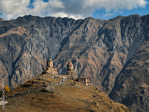 Gergeti Trinity Church on a mountain ridge in the Caucasus Mountains, Georgia. Drone view of the ancient stone monastery and high mountain landscape.