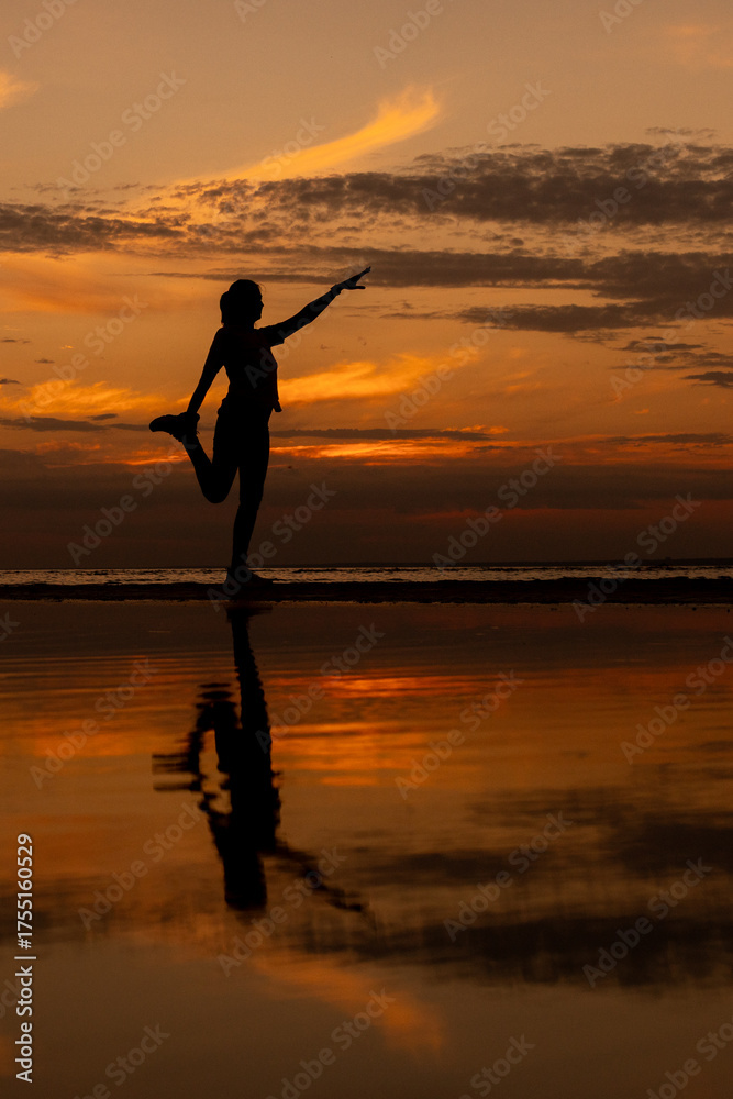 Fototapeta premium yoga and meditation. woman plays sports at sunset on the ocean. doing leg stretching, preparing for a marathon. fitness and yoga in the park, silhouette. life photo.