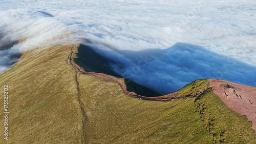 Aerial orbit of Pen-y-Fan summit in Wales with hikers above a temperature inversion