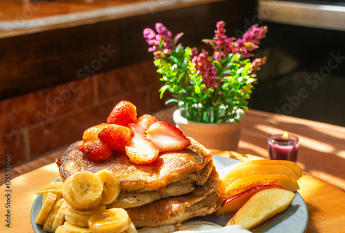 Photography of pancakes with strawberry, banana, and apple fruits with natural light and a kitchen background
