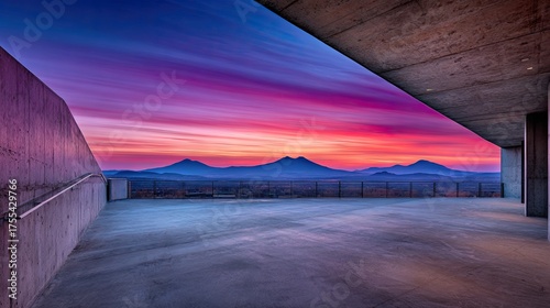 Dramatic sunset view from modern structure with mountains in the background