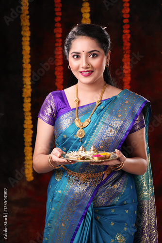 Beautiful Indian women or girl holding pooja thali in Diwali festival wearing Indian traditional costume like saree and blouse isolated on dark diwali festival background  