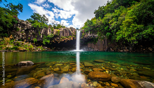 Stunning Waterfall in Lush Tropical Landscape with Clear Emerald Pool and Rocky Surroundings.