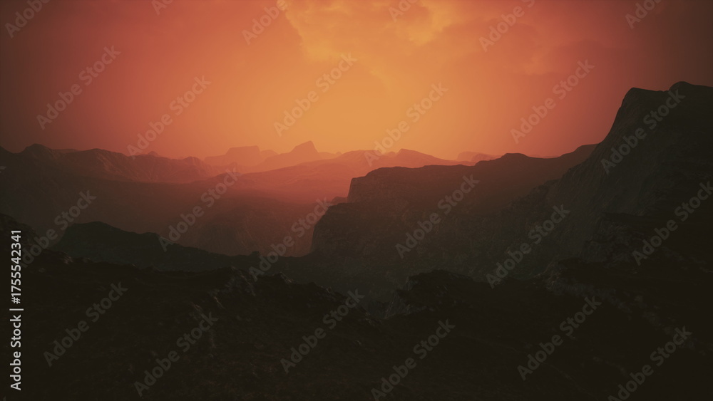 Obraz premium A vibrant sunset casts hues of orange and red over jagged mountain peaks. The landscape is tranquil, evoking a sense of peace as day transitions into night. Shadows deepen in the valleys.