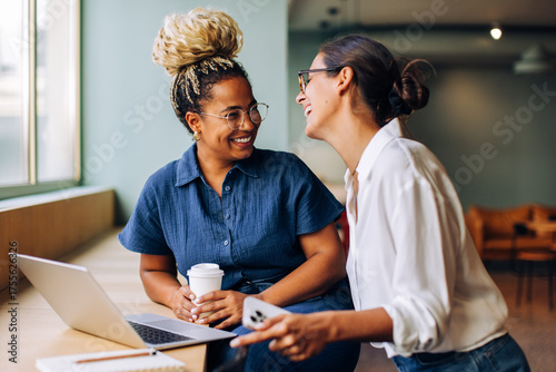 Papier peint Two women enjoying a cheerful conversation by a laptop