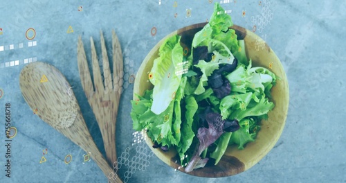 Showing wooden salad bowl holding lettuce on grey countertop, with wooden servers and tech overlays