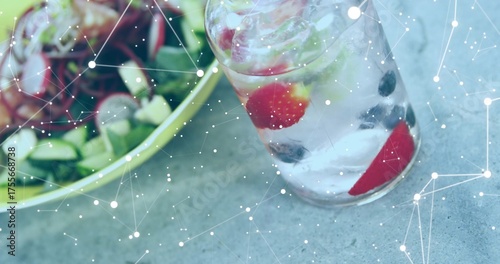 Showing glass holding iced fruit-infused water mint beside salad bowl on stone tabletop, copy space