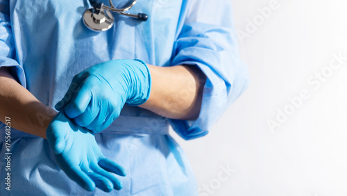 Healthcare professional putting on blue medical gloves on white background with copy space