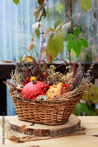 Quadro su tela Florist at work: woman shows how to make seasonal autumn table decoration with pumpkins, flowers and plants in a wicker basket