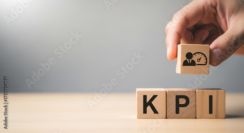 Hand placing a wooden block with a performance indicator icon on top of blocks spelling out KPI on a wooden surface
