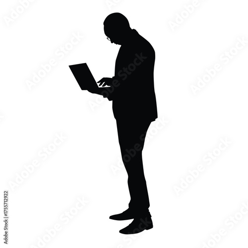 Silhouette of a man in a business suit and glasses standing, holding and typing on a laptop computer. Ideal for concepts of mobile work, technology, professional communication, or digital business