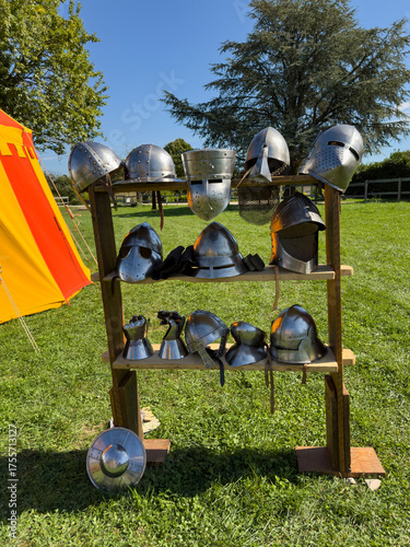 Collection of Medieval Knight Helmets on a Wooden Display Rack Outdoors