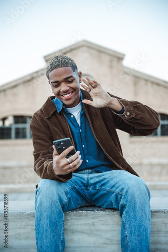 Man making a video call on the phone greeting and smiling outside