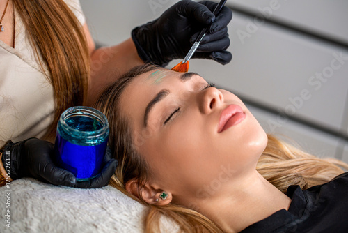 Doctor hand esthetician applying glycolic acid peel on face of young woman. Young woman getting a facial mask treatment at the beauty salon. Facial skin care procedures