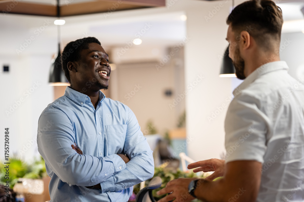 Obraz premium Happy colleagues having friendly conversation in modern office