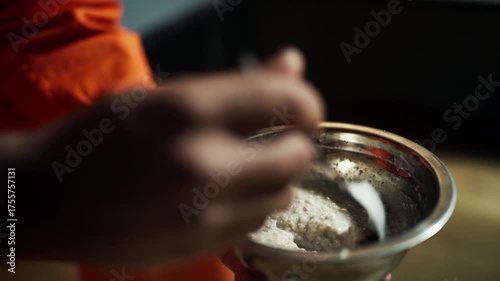 Convicted man in orange robe eating tasteless food during solitary confinement