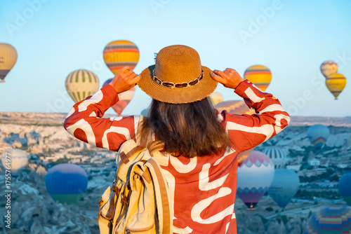 Hot air balloon festival in Cappadocia at sunrise with a traveler admiring the colorful balloons in the sky