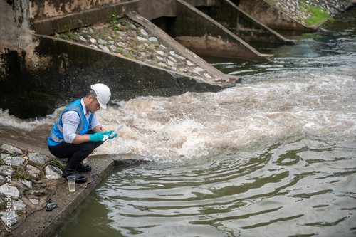 Wastewater treatment worker is collecting samples of water from a public well
