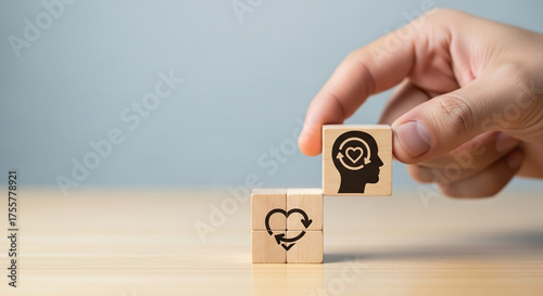 Person's hand places wooden block with head and heart icon, symbolizing self care and mental wellness journey