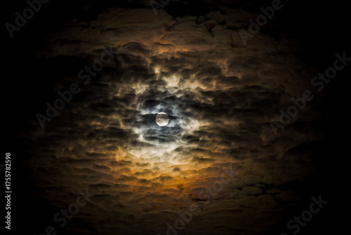 Full moon on a dark cloudy night with clouds flying in front of the moon like in thrillers and horror movies. Dark night sky, black clouds. Real shooting