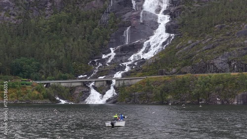 Langfossen waterfall flows near fishing vessel in remote Norway view