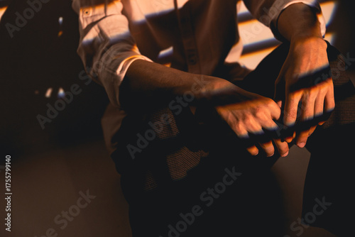 Close-up of male hands in warm sunlight with artistic shadow patterns creating a moody and elegant composition