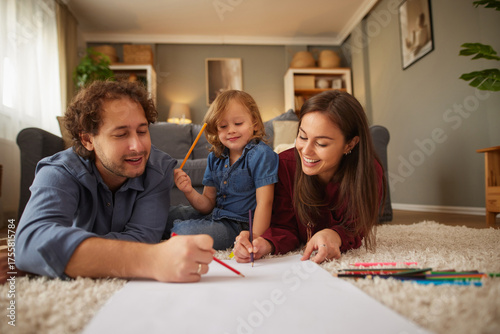 A joyful family spends quality time together, lying on a soft carpet, drawing and painting. They share laughter and creativity in a warm living room setting.