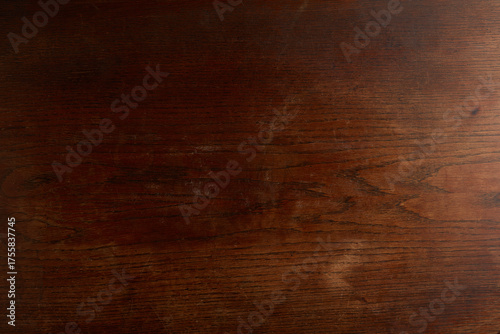 Dark rich brown wooden texture background with visible grain and subtle scratches, resembling an antique mahogany or walnut surface.
