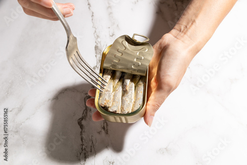 Female hands eating sardines on kitchen countertop background