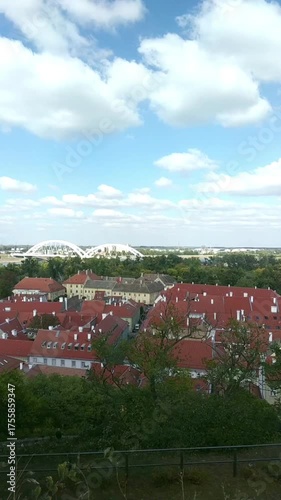 View from fortress wall toward Petrovaradin and Novi Sad: red rooftops, Žeželj Bridge, and St. George’s Church. Concepts of architectural diversity, cross-river connection, and European urban history.