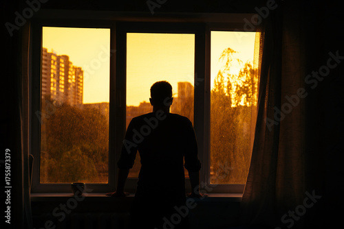 Man watching sunrise through window