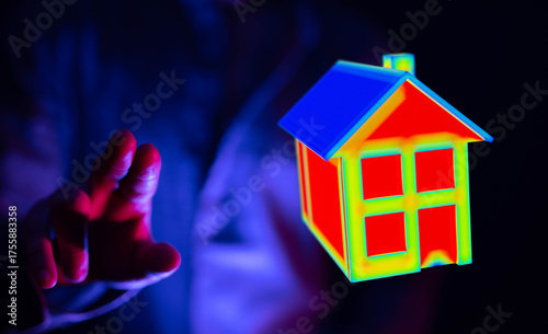 A hand touches a house model with a colorful heat map effect, illustrating home energy, concept of smart home