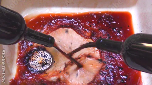 A man pours 2 bottles of spoiled waste red wine to the sink