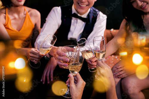 Beautiful woman having fun with group of friends clinking champagne glasses during celebration party. Drink concept.