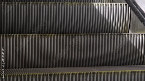 Metallic escalator rising in modern building, symbolizing urban transport, motion, and technology.