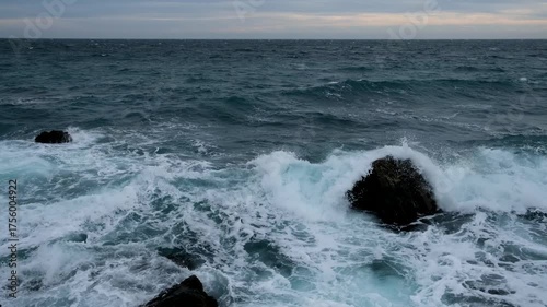 Turquoise sea stone beach, breaking waves on a cloudy spring day. Beautiful sea background. The concept of summer, vacation, travel. The purest clear sea water, large stones on the beach close-up