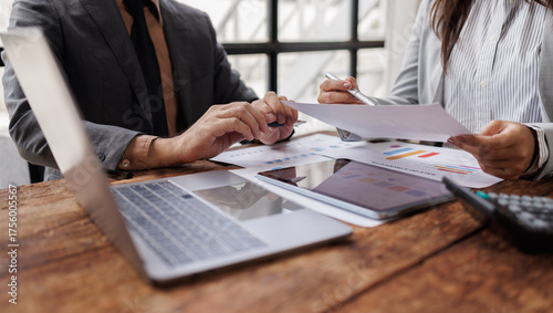Business team holding pen colleagues reviewing financial data and discussing investment strategies

