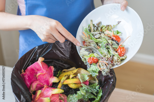 Compost from leftover food housekeeper woman, female hand holding salad dish or plate use fork scraping waste, rotten vegetable throwing away into garbage, trash or bin. Environmentally responsible.