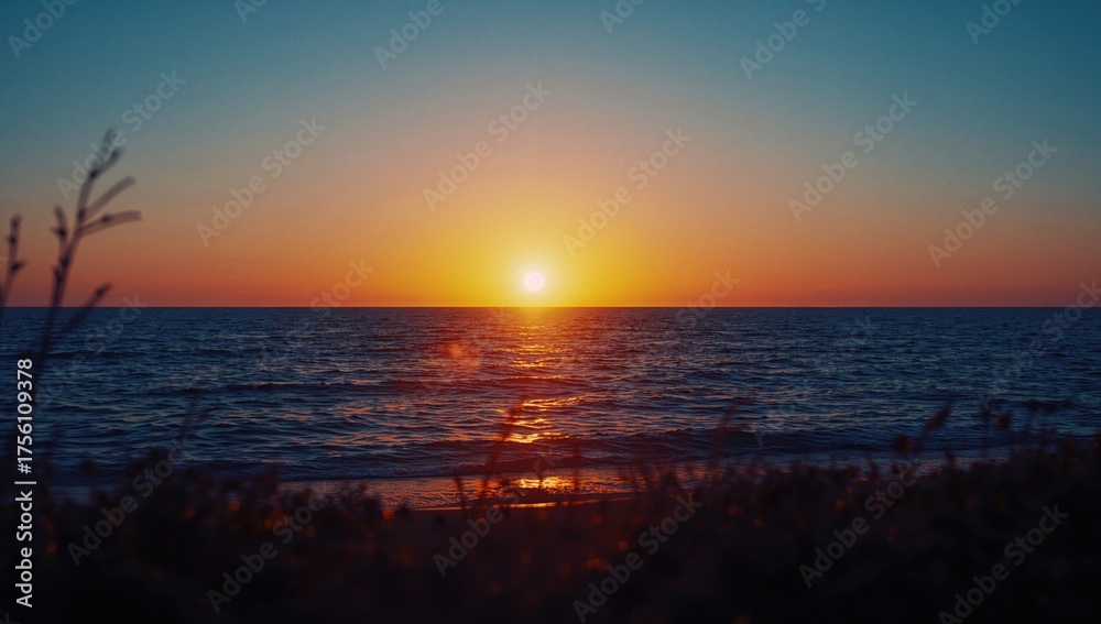 Naklejka premium A tranquil dusk by the ocean paints a mesmerizing picture, with shimmering waves illuminated by the fading sunlight and soft-focus vegetation outlines in front.
