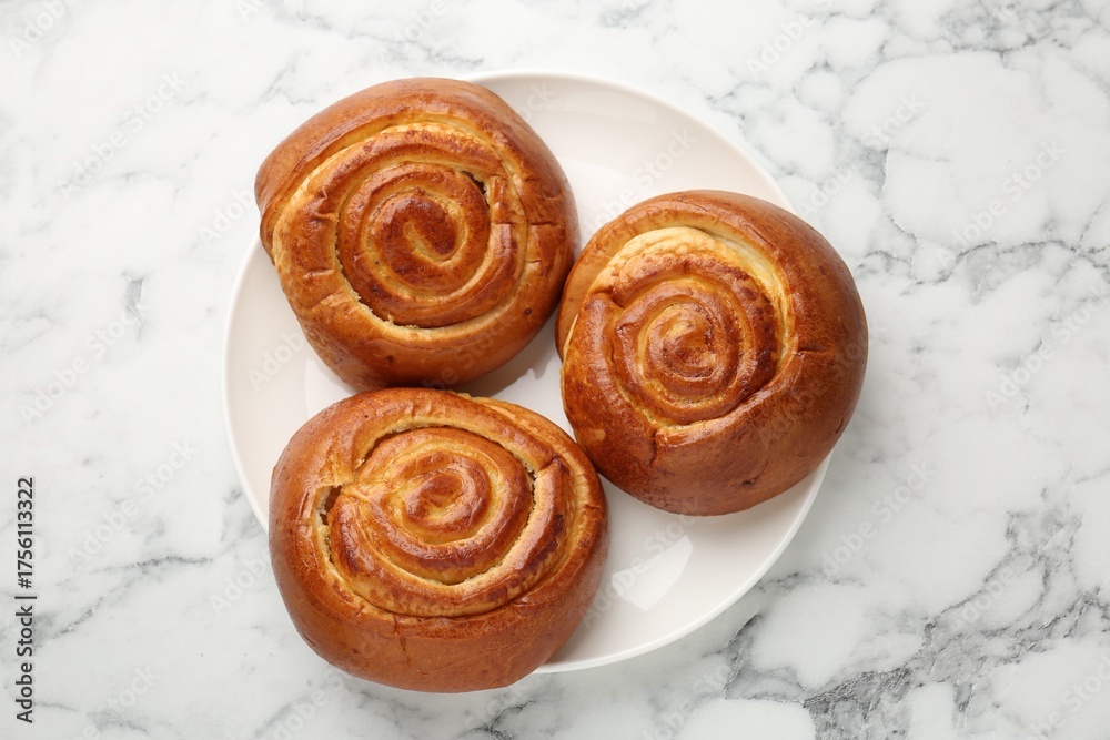 Fototapeta premium Tasty roll buns on white marble table, top view