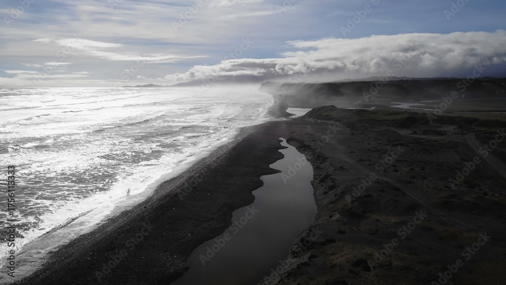 Fototapeta premium Fog rolling over black sand beach and river estuary