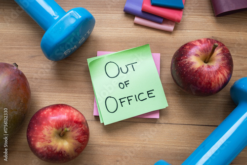 Green “Out of Office” Sticky Note Surrounded by Fruit and Fitness Accessories
