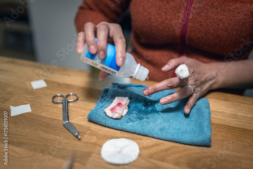 Hand of woman pouring disinfectant liquid on finger for cleaning wound