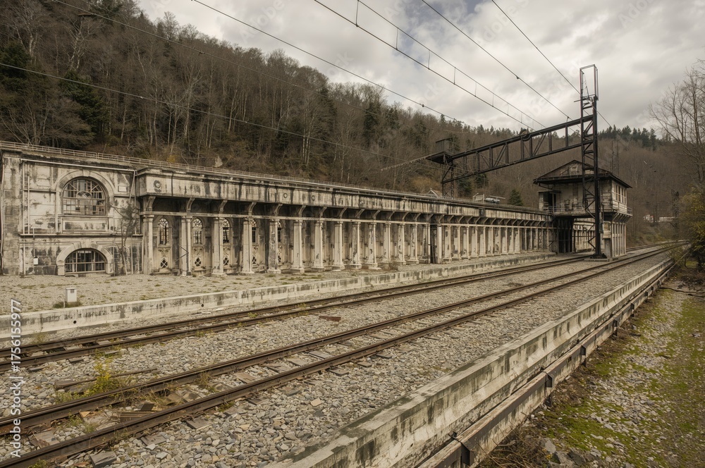 Obraz premium Deserted quarry adjacent to a disused railway track with decaying industrial structures and buildings