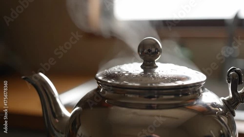 Close up of a shiny silver teapot with steam rising upwards