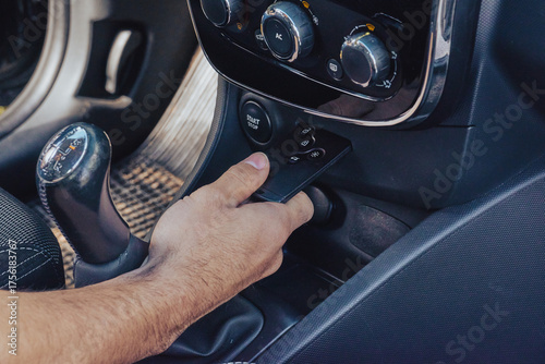 Wallpaper Mural Male hand holds keyless remote by dashboard and start controls in modern car interior, secure entry and ignition concept Torontodigital.ca